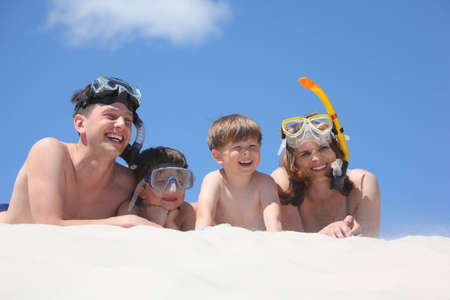 family of four lying on sand with snorkeling masksの写真素材