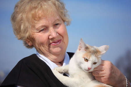 Portrait of aged woman with cat on skyの写真素材