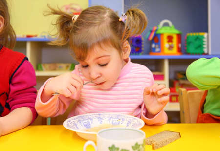 Little girl eats in kindergartenの写真素材