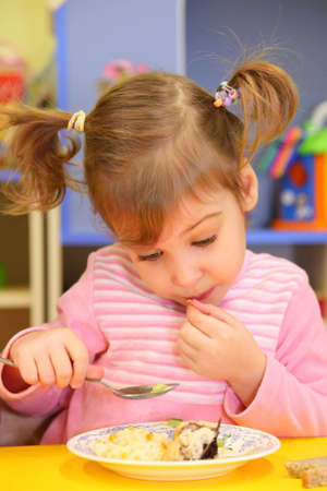 Little girl eats in kindergartenの写真素材