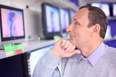 elderly man in shop looks at TVの写真素材