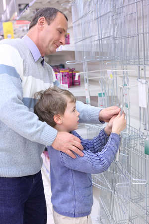 elderly man with boy in store hang grill for roasting on wallの写真素材