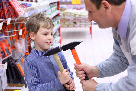 elderly man with boy in shop with hammers in handsの写真素材