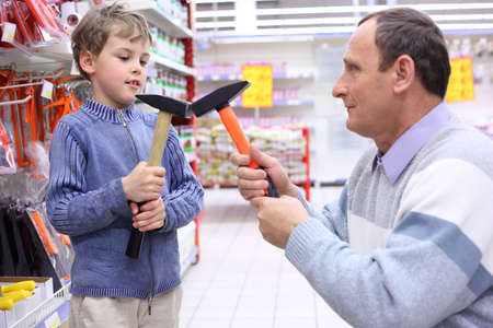 elderly man with boy in shop with hammers in handsの写真素材