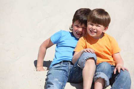 Two children sit on sandの写真素材
