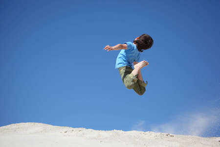 boy jumps on sand の写真素材
