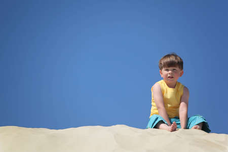 boy sits on sandの写真素材