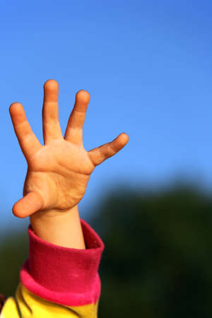 children's hand against sky