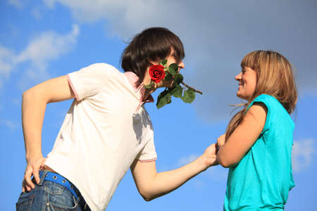 guy with rose in mouth and girl against skyの写真素材
