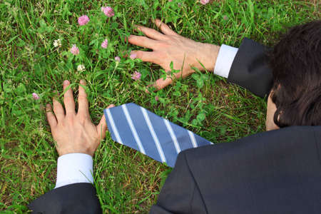 businessman lies prone on grass, top viewの写真素材