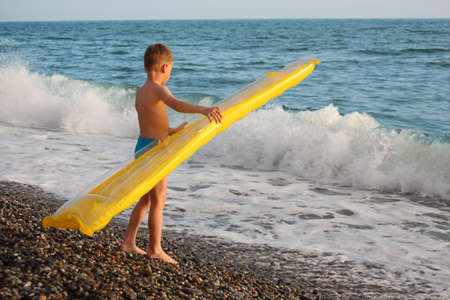 boy with inflatable mattress stands on seacoastの写真素材