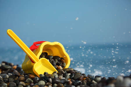 Yellow children's bucket with  scoop on stone seacoastの写真素材