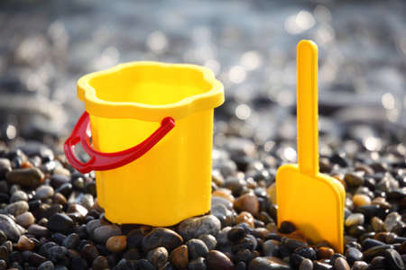 Yellow children's bucket with  scoop on stone seacoastの写真素材