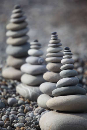four stone stacks on pebble beach on stone backgroundの写真素材