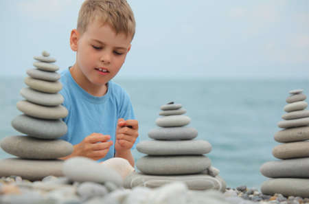 boy and stone stacks on pebble beachの写真素材