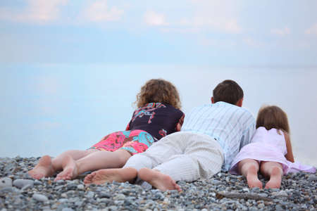 Happy family with little girl lying on stony beach, lying backの写真素材