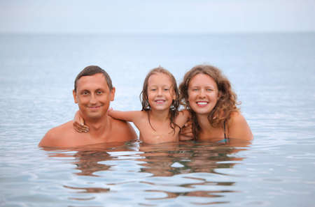 Happy family with little girl bathe in seaの写真素材