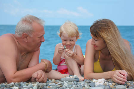 Mother and grandfather with child on sea coast 