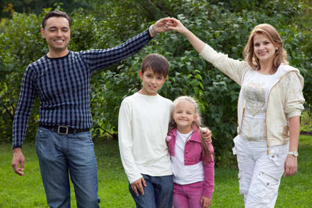 parents playing with children in park, making house