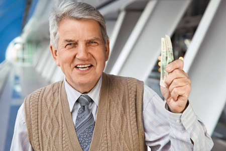 Senior man in the building holding russian moneyの写真素材