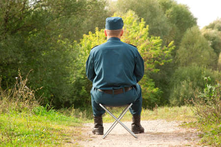 military man sitting back on the camp-chair outdoorsの写真素材
