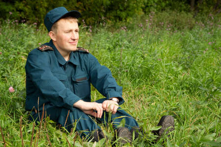 military man sitting in green fieldの写真素材
