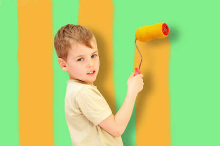 a boy with a roller draws yellow bars on green wall, collageの写真素材