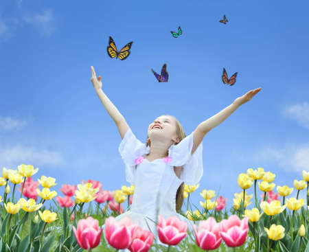 little girl in tulips with hands up and butterfly collageの写真素材