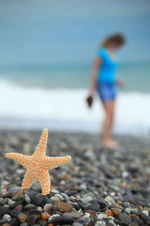 Starfish and young girl on stone seacoastの写真素材