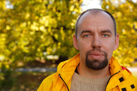 Portrait of man with beard in autumn park sunny day. Close-up.