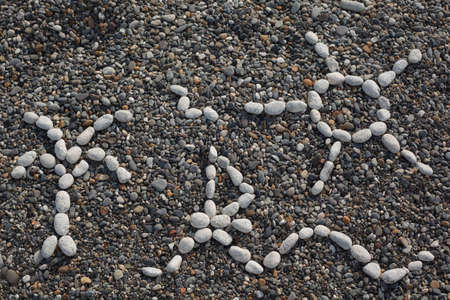 Beach - drawing combined from white stones against dark pebble.の写真素材
