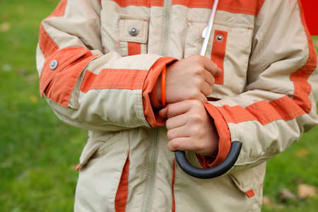 Hands of boy in jacket hold umbrella handle. Ñlose up. Horizontal format.の写真素材