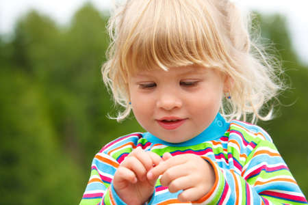 Portrait of little girl in stripe clothe with earrings in park. A close up.の写真素材