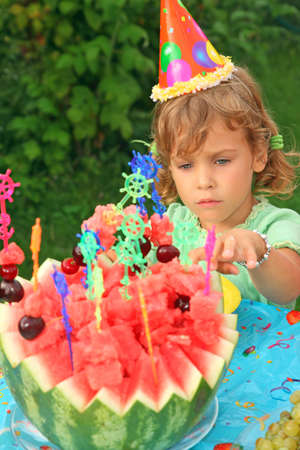 little girl in cap eats fruit in garden, happy birthdayの写真素材