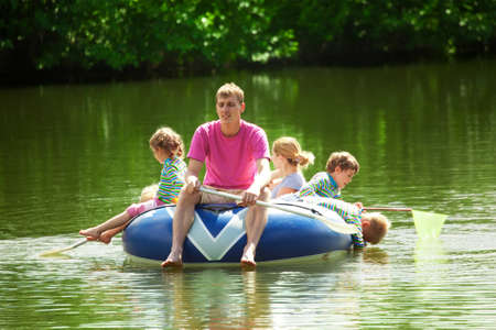Children and adults float on an inflatable boat in a sunny dayの写真素材