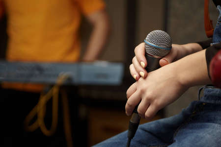 microphone in hand of vocalist girl. keyboard player in out of focusの写真素材