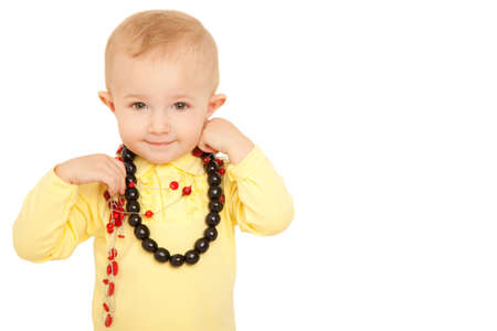 Portrait of smiling little girl looks into camera in yellow shirt with beads on white background.の写真素材