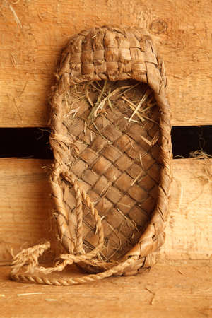 Rural still life. Russian traditional bast shoes on background of  boards. Vertical format.の写真素材
