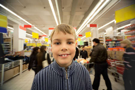 Smilling boy stand in centre of trading floor in supermarketの写真素材
