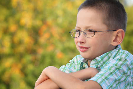portrait of little boy with arms across in early fall park. he is looking away.の写真素材