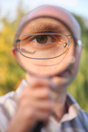 man with glasses in early fall park looking through      magnifierの写真素材