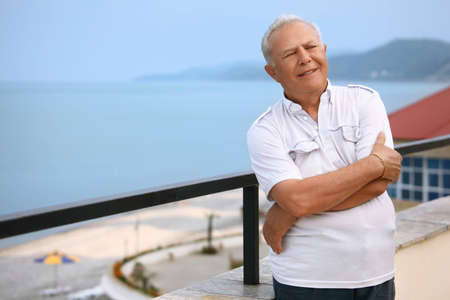 smiling senior on veranda near seacoastの写真素材