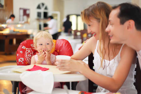 Happy family with blond little girl eating breadの写真素材