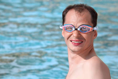 smiling young man in watersport goggles swimming in poolの写真素材
