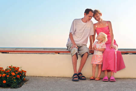 Happy family with little sitting on bench on resortの写真素材