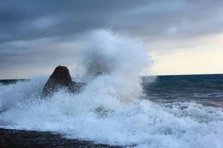 Sea coast with waves breaking about stoneの写真素材