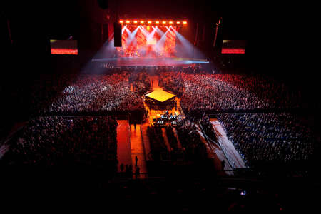 musical performance concert. red one light. light show. group band singer is performing dancing on...