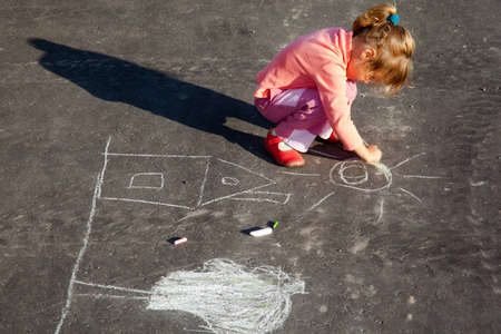 girl draws painting line a chalk on asphalt.の写真素材