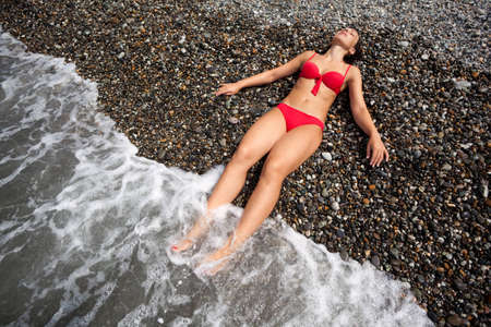 attractive woman lying on beach. young girl lies in waves on seacoastの写真素材