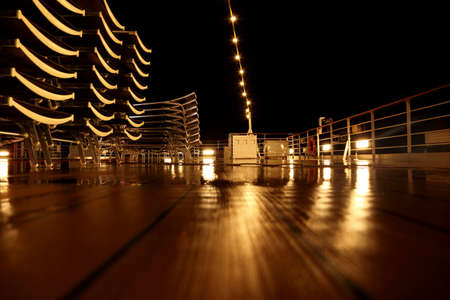 empty cruise ship deck with beach chairs and lamps at night timeの写真素材